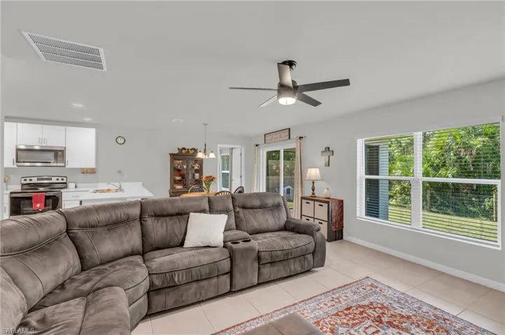 Tiled living room featuring sink and ceiling fan with notable chandelier