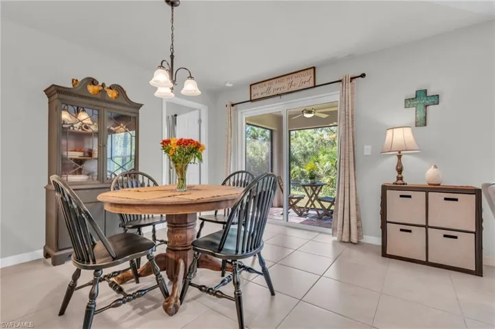 Tiled dining area with ceiling fan with notable chandelier