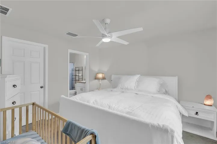 Bedroom featuring connected bathroom, ceiling fan, and dark colored carpet