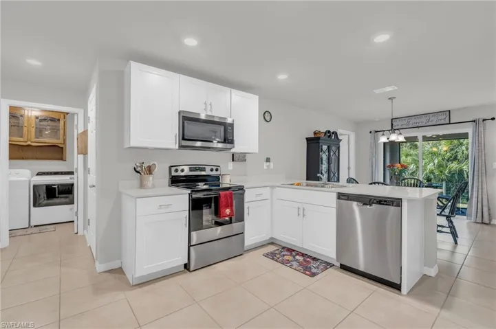 Kitchen with washer and dryer, appliances with stainless steel finishes, kitchen peninsula, and white cabinets