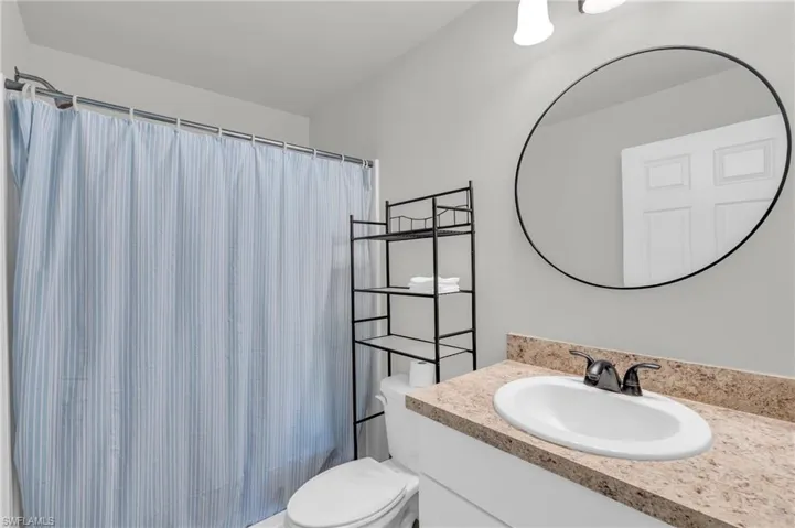 Bathroom featuring vanity, toilet, and curtained shower