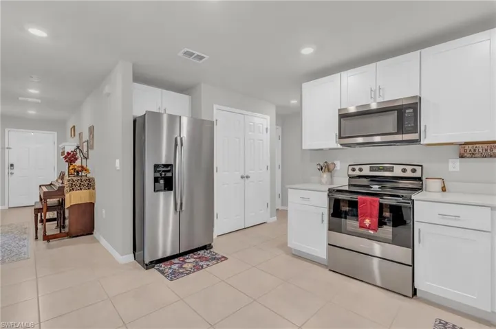 Kitchen featuring stainless steel appliances, light tile patterned flooring, and white cabinets