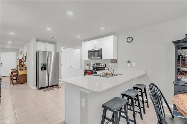 Kitchen with kitchen peninsula, white cabinets, a kitchen breakfast bar, sink, and stainless steel appliances