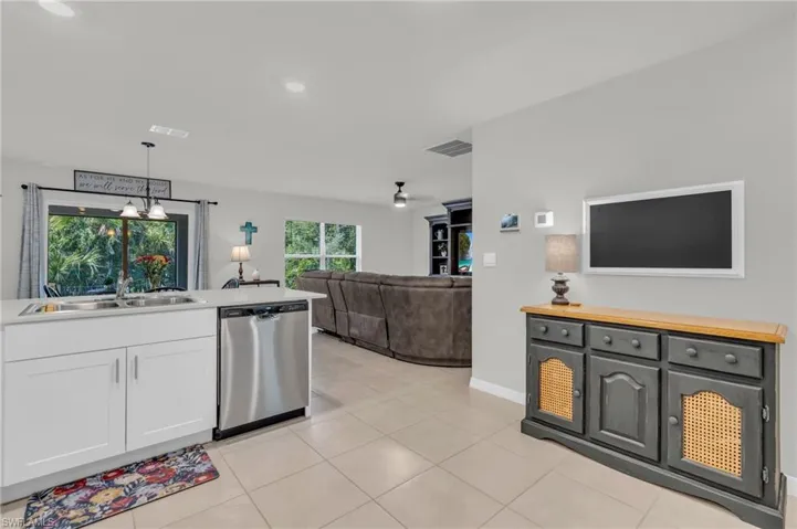 Kitchen featuring sink, wood counters, white cabinetry, decorative light fixtures, and stainless steel dishwasher