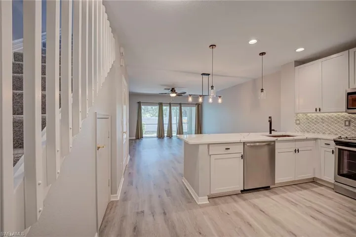 Kitchen featuring white cabinetry, decorative backsplash, stainless steel appliances, and pendant lighting
