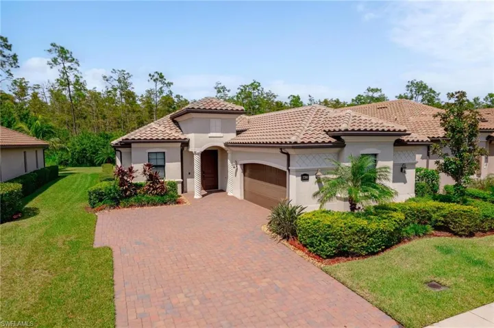 Mediterranean / spanish-style home with a garage and a front lawn