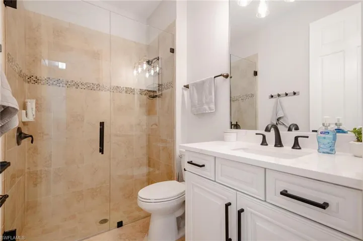Bathroom featuring vanity, an enclosed shower, and toilet