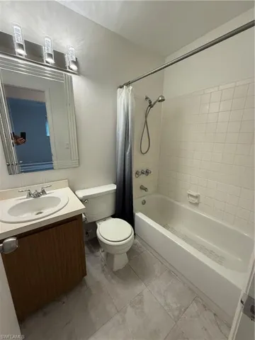 Bathroom with toilet, shower / tub combo, and vanity