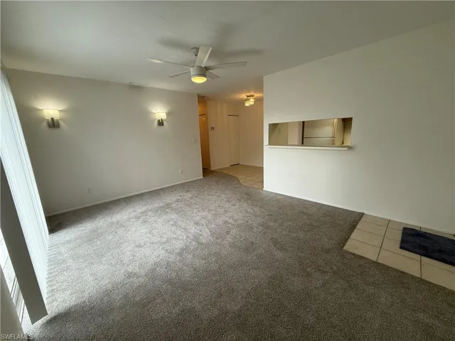 Spare room with light colored carpet, a ceiling fan, and light tile patterned floors