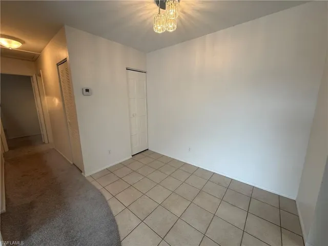 Unfurnished room featuring light tile patterned floors, a chandelier, and baseboards