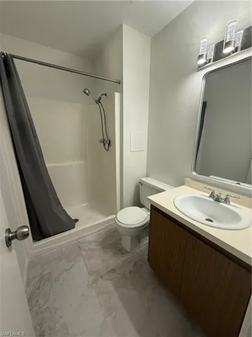 Full bathroom featuring toilet, a shower stall, vanity, and marble finish floors