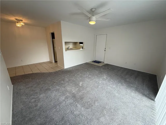 Unfurnished room with carpet flooring, tile patterned floors, and a ceiling fan