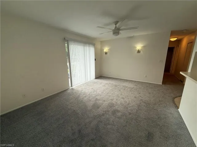 Carpeted empty room featuring ceiling fan and baseboards