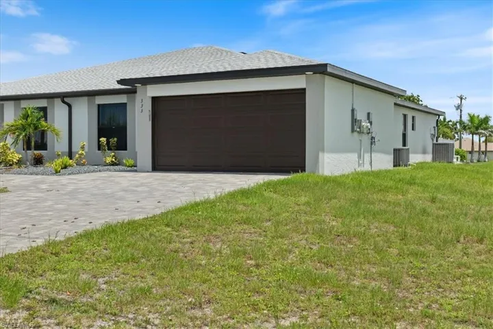 View of home's exterior featuring a yard, stucco siding, decorative driveway, and a garage