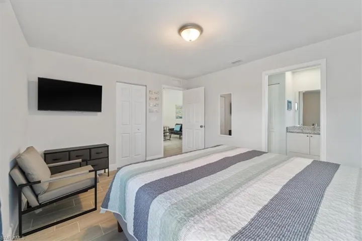 Bedroom featuring wood tiled floors, ensuite bathroom, and a closet