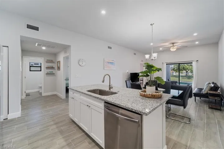 Kitchen with light stone counters, dishwasher, wood tiled floors, white cabinets, and a ceiling fan