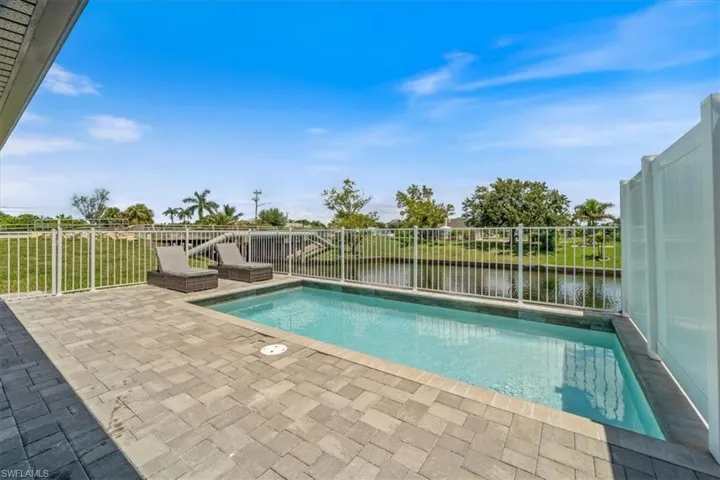 View of pool with a fenced backyard, patio surround, and a water view