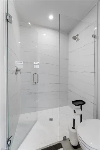 Bathroom featuring a marble finish shower and toilet