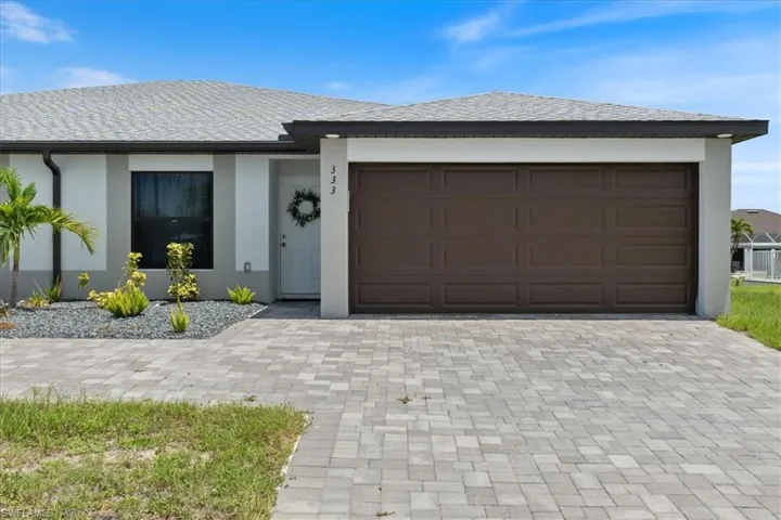 View of front facade featuring stucco siding, driveway, a garage, and a shingled roof