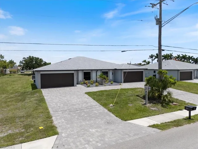 Ranch-style home with a front yard, a shingled roof, a garage, and decorative driveway