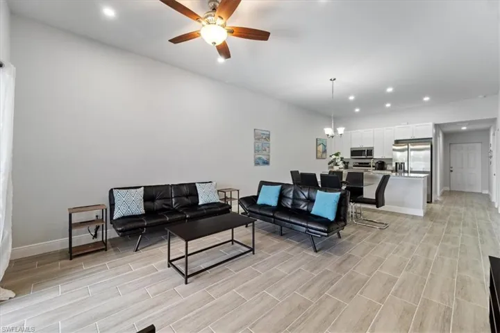 Living room featuring hanging lights, ceiling fan, and wood tiled floors