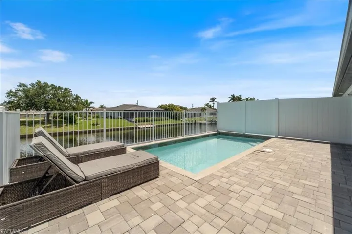 View of swimming pool with patio surround, a water view, and a fenced backyard
