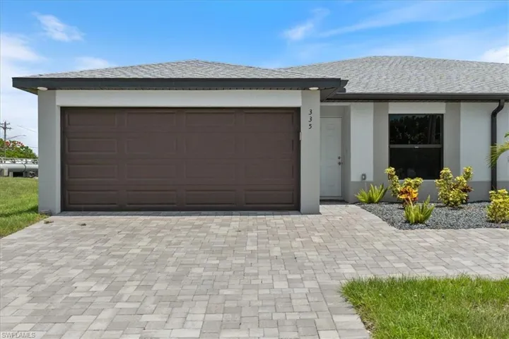 View of front of property featuring decorative driveway, stucco siding, and a shingled roof