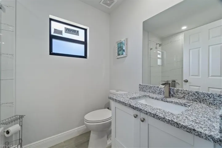 Full bath featuring vanity, a marble finish shower, and light tile patterned floors