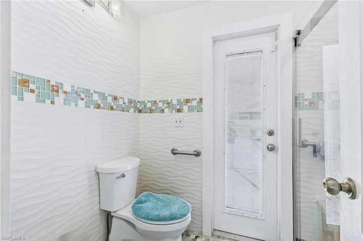 The updated primary bathroom features modern finishes and convenient access to the pool area.