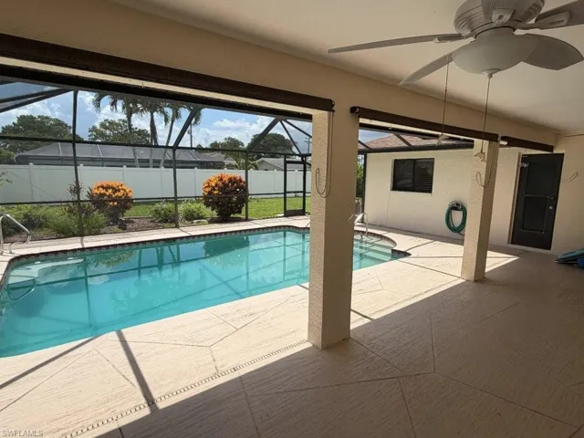 Screened-in pool area featuring a rectangular pool with an attached spa