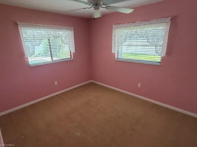 Guest bedroom - Carpeted room featuring two windows with horizontal blinds and valances, light pink wall paint, white baseboards, and a ceiling fan