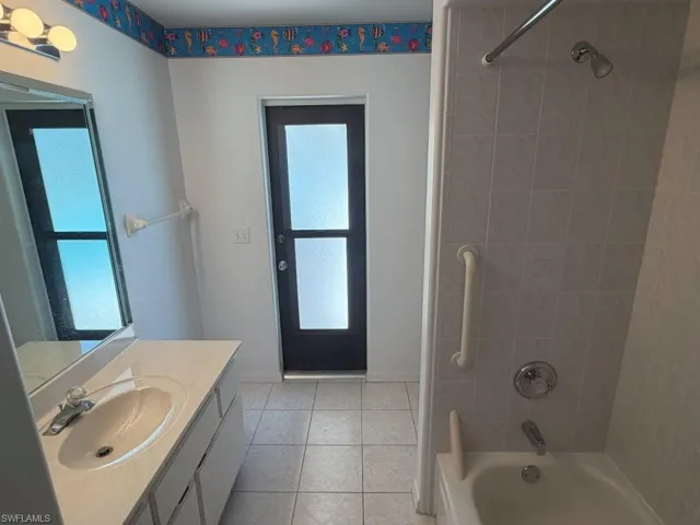 Guest Bathroom with POOL ACCESS, featuring a single vanity, tiled shower-tub combination, and tiled flooring