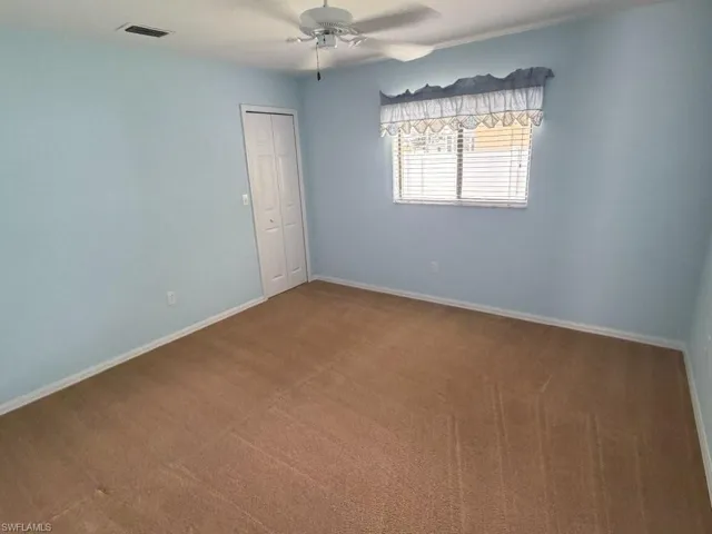 Guest bedroom - Carpeted interior room featuring light blue walls, a white ceiling fan, and a window with horizontal blinds