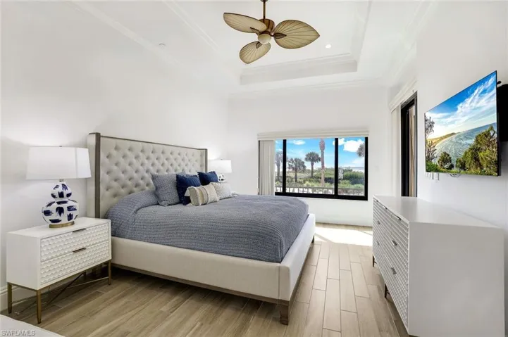 Bedroom featuring ceiling fan, a raised ceiling, light wood-type flooring, and ornamental molding