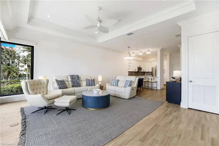 Living room with ornamental molding, light wood-type flooring, and a tray ceiling