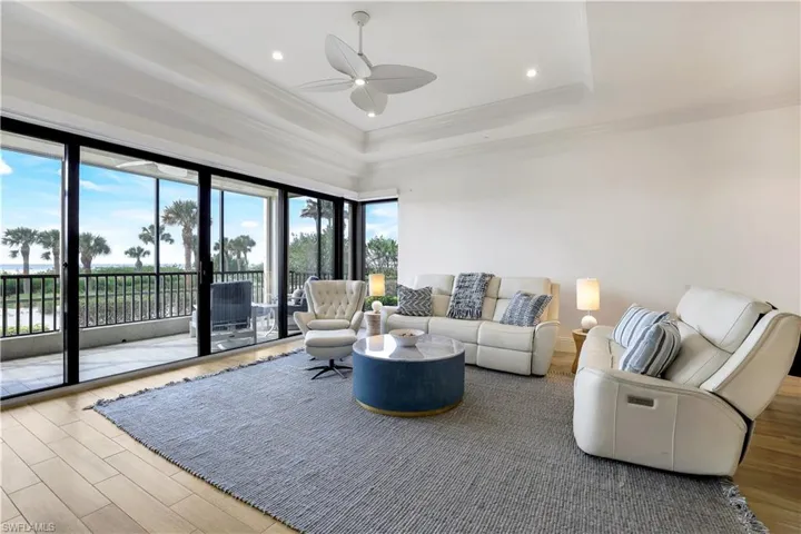 Living room with ceiling fan, wood-type flooring, crown molding, and a tray ceiling