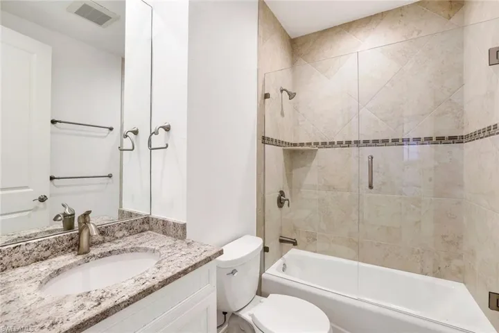 Full bathroom with bath / shower combo with glass door, vanity, and toilet