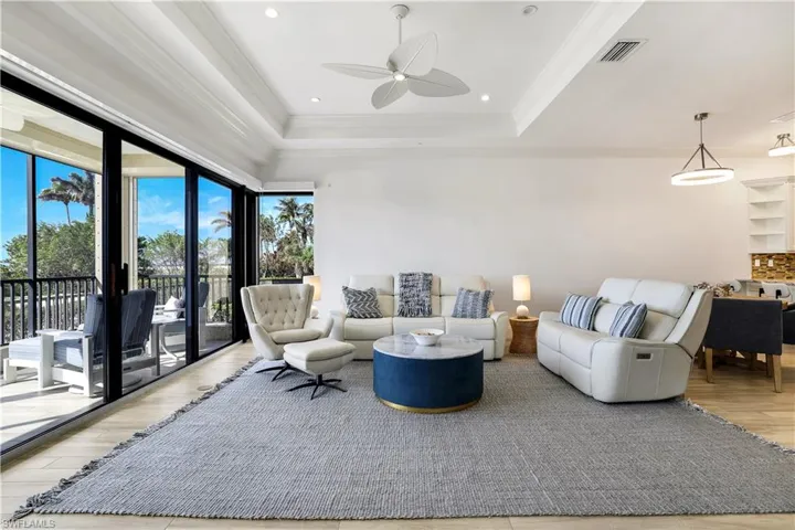 Living room featuring ornamental molding, light hardwood / wood-style flooring, ceiling fan, and a raised ceiling