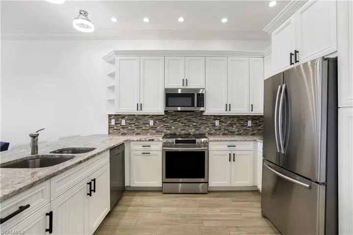 Kitchen featuring stainless steel appliances, white cabinetry, and sink