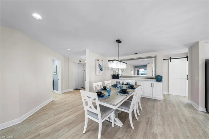 Dining area with a barn door, light wood-type flooring, and recessed lighting