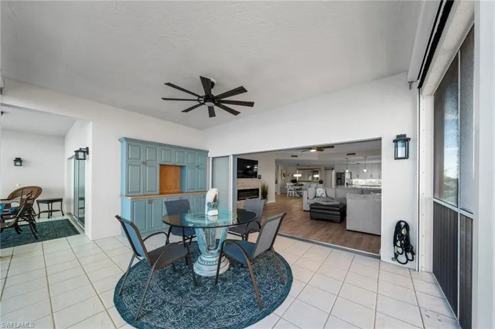 Dining area with light tile patterned floors, a textured ceiling, ceiling fan, and a fireplace