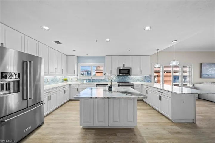 Kitchen with stainless steel appliances, pendant lighting, white cabinets, decorative backsplash, and recessed lighting