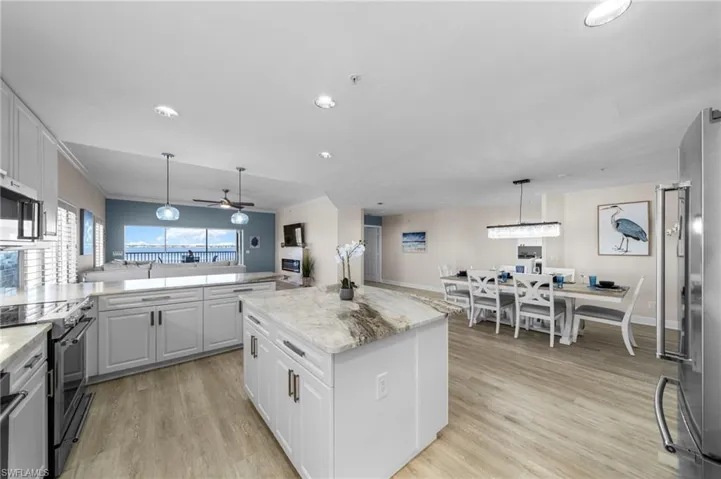 Kitchen with decorative light fixtures, appliances with stainless steel finishes, white cabinetry, open floor plan, and recessed lighting