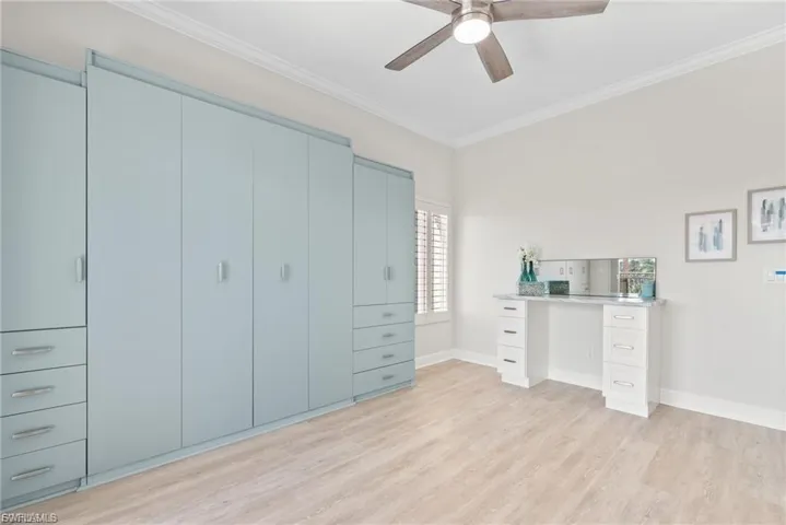 Bedroom with crown molding, light wood-style flooring, ceiling fan, and a desk