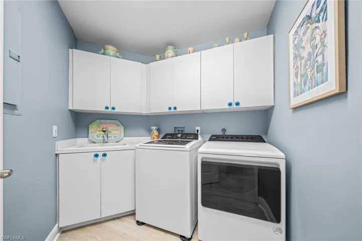 Washroom with washer and clothes dryer, cabinet space, and light wood-style floors