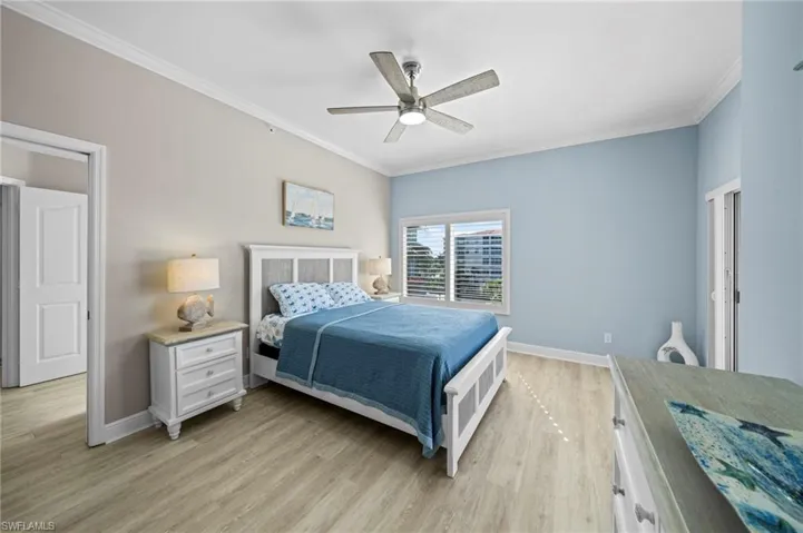 Bedroom with ornamental molding, light wood-style flooring, and ceiling fan