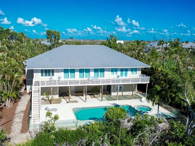Rear view of house with a patio area, a metal roof, stairway, a pool with connected hot tub, and view of wooded area