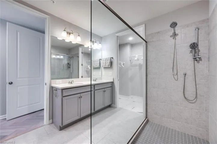 Primary bath with a tile shower, double vanity, and a spacious closet