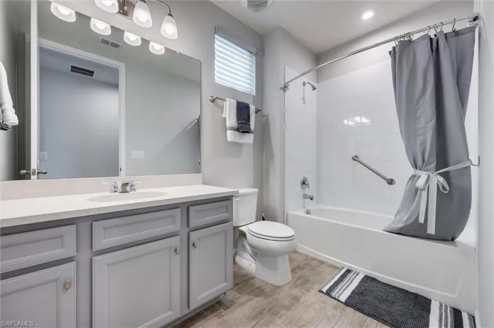 Guest bath featuring shower / bathtub combination with curtain, vanity, and light wood-style floors
