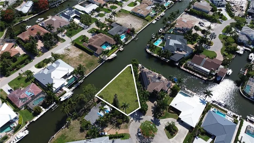 Aerial perspective of suburban area with a nearby body of water and property boundaries highlighted